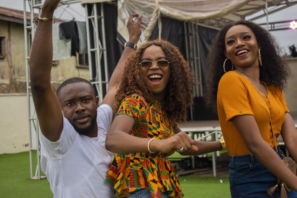 Group of young, cheerful Nigerian friends dancing with big smiles at a concert