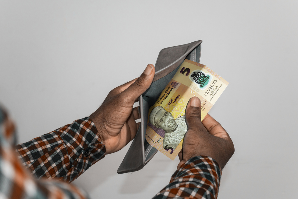 Black hands Holding empty opened men wallet containing single Two Nigerian Naira note. hand removing money out of wallet. no money poor person concept